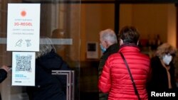 People pass by a sign spelling out COVID-19 rules at the entrance to the Dresden State Art Collections, in Dresden, Germany, Nov. 19, 2021.