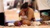 A refugee woman from the minority Yazidi sect, who fled the violence in the Iraqi town of Sinjar, sits with a child inside a tent at Nowruz refugee camp in Qamishli, northeastern Syria, Aug. 17, 2014. 