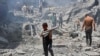 Seorang anak laki-laki membawa barang-barang yang berhasil diselamatkan dari puing-puing bangunan yang hancur akibat pengeboman Israel di kamp pengungsi al-Shati di Kota Gaza pada 22 Juni 2024. (Foto: AFP)