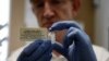 FILE - A researcher holds a vial of an experimental Ebola vaccine in Oxford, England.