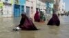 FILE - People wade through a flooded street in Beledweyne, central Somalia, in this image made from video, May 17, 2020. 
