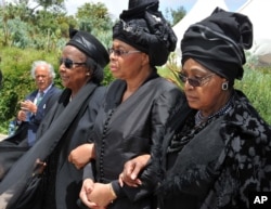 FILE - Winnie Madikizela-Mandela, right, Nelson Mandela's former wife, and Nelson Mandela’s widow Graca Machel, center, walk from the funeral service to the burial site of former South African President Nelson Mandela in Qunu, South Africa.