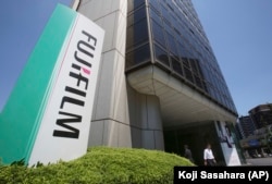 Seorang pria berjalan di depan kantor pusat Fujifilm Holdings Corporation di Nishiazabu di Tokyo, Senin, 14 Mei 2018. (Foto: AP/Koji Sasahara)