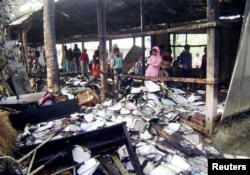 People look at burnt textbooks after a primary school which was supposed to be used as a polling booth was set on fire, in Feni, Bangladesh, Jan. 4, 2014.