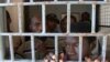 FILE - African migrants look through bars of a locked door at Sabratha migrant detention center for men in Sabratha, Libya, Oct. 2013.