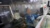 FILE - An employee working on the production line of an electronics factory is seen reflected on an equipment, in Jiaxing, Zhejiang province, China, April 2, 2019.
