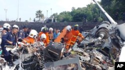 Sejumlah petugas damkar Malaysia memeriksa lokasi tabrakan dua helikopter di Lumur, negara bagian Perak, Malaysia, 23 April 2024. (Foto: Fire & Rescue Department of Malaysia via AP)
