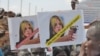 A protester holds up signs protesting against UNMISS head Hilde Johnson at a rally in Juba after South Sudanese government forces found weapons in a UN overland shipment.