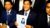 Leader of Thai Raksa Chart party Preecha Pholphongpanich, center, holds a picture of Princess Ubolratana at election commission of Thailand in Bangkok, Feb. 8, 2019. The political party has selected the princess as its nominee as the next prime minister.