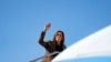 A vice-presidente dos EUA e candidata democrata à presidência, Kamala Harris, acena enquanto embarca no Air Force Two no Aeroporto Internacional Sky Harbor em Phoenix, Arizona, a 11 de outubro de 2024. 