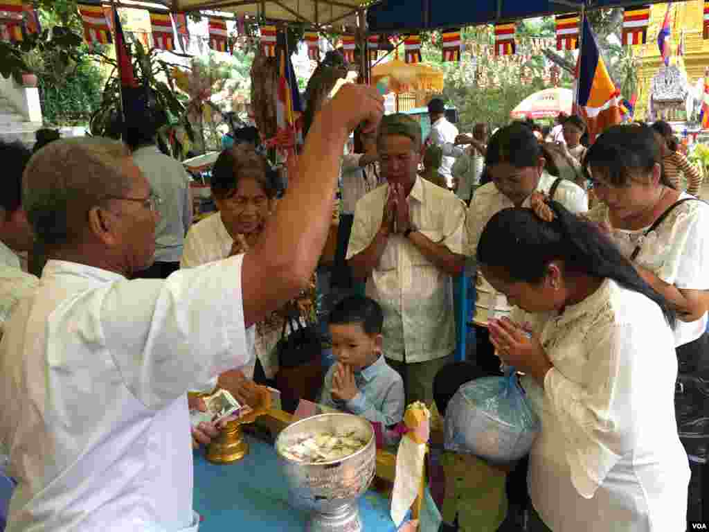 ពុទ្ធបរិស័ទកំពុងឈរទទួលពរនៅក្នុងវត្តមួយកណ្តាលរាជធានីភ្នំពេញកាលពីព្រឹកថ្ងៃសៅរ៍ ទី១៦ ខែ កញ្ញា ឆ្នាំ២០១៧។(កាន់វិច្ឆិកា/VOA)