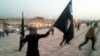 FILE - A fighter of the Islamic State holds up an IS flag and a weapon on a street in Mosul, Iraq.