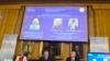 Members of the Nobel Committee for Physics sit in front of a screen displaying portraits of Arthur Ashkin of the United States, Gerard Mourou of France and Donna Strickland of Canada during the announcement of the winners of the 2018 Nobel Prize in Physic