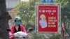 Một người lái xe máy qua một poster kêu gọi người dân bảo vệ sức khoẻ trước virus corona trên một đường phố ở Hà Nội hôm 14/4. CSIS nói người dân Việt Nam đồng thuận với sự giám sát của chính phủ nhằm ngăn chặn sự lây lan của dịch bệnh.
