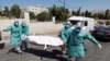 Personal médico palestino carga el cuerpo de una persona fallecida a causa del coronavirus para ser enterrado en un cementerio en Hebrón. 29 de junio de 2020.