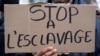 A man holds a placard with the message "Stop slavery" as he attends a protest against slavery in Libya outside the Libyan Embassy in Paris, France, Nov. 24, 2017.