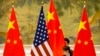 Seorang pegawa sedang memperbaiki posisi bendera AS dan China sebelum sesi pembukaan pembicaraan dagang antara perwakilan AS dan China di Beijing, 14 Februari 2019. (Foto: Mark Schiefelbein/AP Photo)