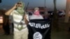 A fighter of the Islamic State of Iraq and the Levant (ISIL) holds a weapon while another holds a flag in the city of Mosul, June 23, 2014. 