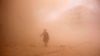 FILE - A rebel fighter runs through dust towards an area damaged by what activists said were barrel bombs dropped by warplanes loyal to Syria's President Bashar al-Assad in Aleppo, Nov. 6, 2014. 