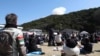 Visitors look on as smoke rises from behind a hill after a small rocket by Tokyo-based startup Space One exploded upon take-off, at the Spaceport Kili site in Kushimoto, Wakayama prefecture, on March 13, 2024.