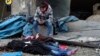 This photo provided by the Syrian Civil Defense White Helmets, which has been authenticated based on its contents and other AP reporting, shows a Syrian boy sitting next to bodies after artillery fire struck the Jub al-Quba district in Aleppo, Syria, Nov.