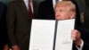 President Donald Trump holds up a signed memorandum calling for a trade investigation of China, Aug. 14, 2017, in the Diplomatic Reception Room of the White House in Washington.