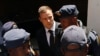 FILE - South African Olympic and Paralympic sprinter Oscar Pistorius (C) is escorted to a police van. The Supreme Court dismissed prosecutors' attempt to change his conviction for culpable homicide to the more serious charge of murder.