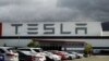 FILE - Vehicles are parked outside the Tesla plant in Fremont, Calif., May 12, 2020.