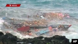 An TV grab shows people floating amid and hanging onto the splintered remains of the wooden boat carrying refugees traveling from Asia after it smashed into the rocky coastline of Christmas Island in rough sea, (File)