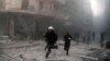 Emergency responders rush following a reported barrel bomb attack by government forces in the Al-Muasalat area in the northern Syrian city of Aleppo, Nov. 6, 2014. 