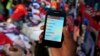 A man holds up his mobile phone showing an M-Pesa mobile money transaction page at an open-air market in Kibera in Kenya's capital, Nairobi, Dec. 31, 2014.
