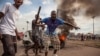 FILE - Demonstrators gather in front of a burning car during an opposition rally in Kinshasa, DRC, Sept. 19, 2016.