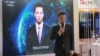 Xinhua news anchor Qiu Hao stands next to an AI virtual news anchor based on him, at a Sogou booth during an expo at the fifth World Internet Conference in Wuzhen town of Jiaxing, Zhejiang province, China, Nov. 7, 2018.