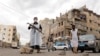 FILE - Security officers wearing protective masks stand on a street during a 24-hour curfew amid concerns about the spread of the coronavirus, in Sanaa, Yemen, May 6, 2020.