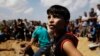 FILE - In this Monday, Aug. 4, 2014 file photo, mourners gather around the graves of members of the Najam family, killed overnight in an Israeli strike in Beit Lahiya, Gaza Strip.