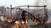 A policeman walks past the smouldering remains of a market in Rubkona near Bentiu in South Sudan, April 23, 2012. 