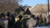FILE - Soldiers in unmarked uniforms sit atop an APC at the gate of the Belbek base near the port city of Sevastopol, Crimea, March 22, 2014. 