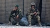 FILE - In this Aug. 5, 2015 photo, an Afghan National Army soldier, left, smokes as a U.S. Army soldier from Charlie Company, 2-14 Infantry Regiment, 2nd Brigade, 10th Mountain Division sits next to him in Camp Khogyani in Nangarhar province, east of Kabul, Afghanistan.