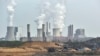 FILE - Giant machines dig for brown coal at the open-cast mining Garzweiler in front of a smoking power plant near the city of Grevenbroich in western Germany.