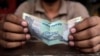 FILE - A cashier holds an Indian rupee. 