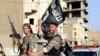Fighters with the militant group Islamic State in Iraq and the Levant (ISIL, also called ISIS by some) wave flags as they take part in a military parade along the streets of Raqqa province, northern Syria, June 30, 2014. 