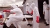 Health workers wearing Ebola protective gear remove the body of a man they suspect died from the Ebola virus, at a USAID, American aid Ebola treatment center on the outskirts of Monrovia, Liberia, Nov. 28, 2014.