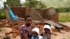 Nomatter Ncube na watoto wake akiwa nje ya nyumba yao iliyokuwa imeharibiwa na kimbunga Idai katika wilaya ya Chimanimani, Zimbabwe, Machi 18, 2019.