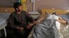 An Afghan wounded man, right, lies on the bed in a hospital as his relative sits on a chair beside him in the city of Kandahar, south of Kabul, Afghanistan, July 9, 2014. 