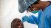 A man opens his mouth for a heath worker to collect a sample for coronavirus testing during the screening and testing campaign aimed to combat the spread of COVID-19 Diepsloot, north Johannesburg, South Africa, May 8, 2020.