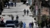FILE - Workers from the Ministry of Health are accompanied by soldiers and police as they investigate in a cordoned off neighborhood after multiple people tested positive for the new coronavirus, in Tegucigalpa, Honduras, March 17, 2020.