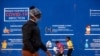 People walk past a COVID-19 advertisement in the township of Soweto outside of Johannesburg, South Africa, July 13, 2020.