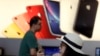 A customer looks at her iPhone in a store of U.S. tech company Apple in Beijing, May 10, 2019. 