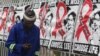 FILE - A man talks on a mobile phone as he walks past World AIDS Day banners in Johannesburg, South Africa, Dec. 1, 2014.